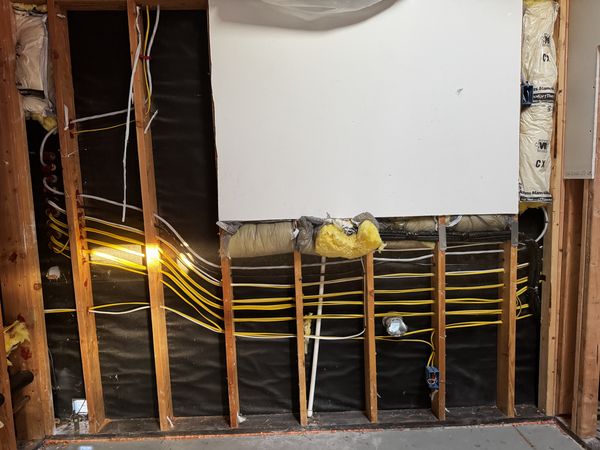 Garage wall opened with new branch circuits routed through the studs
