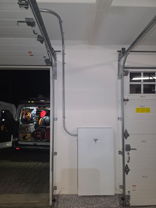 Tesla Wall Connector EV charger with cable neatly coiled on the exterior wall