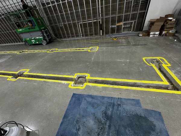 Saw-cut floor trench for new receptacle and power feeds in the concrete slab