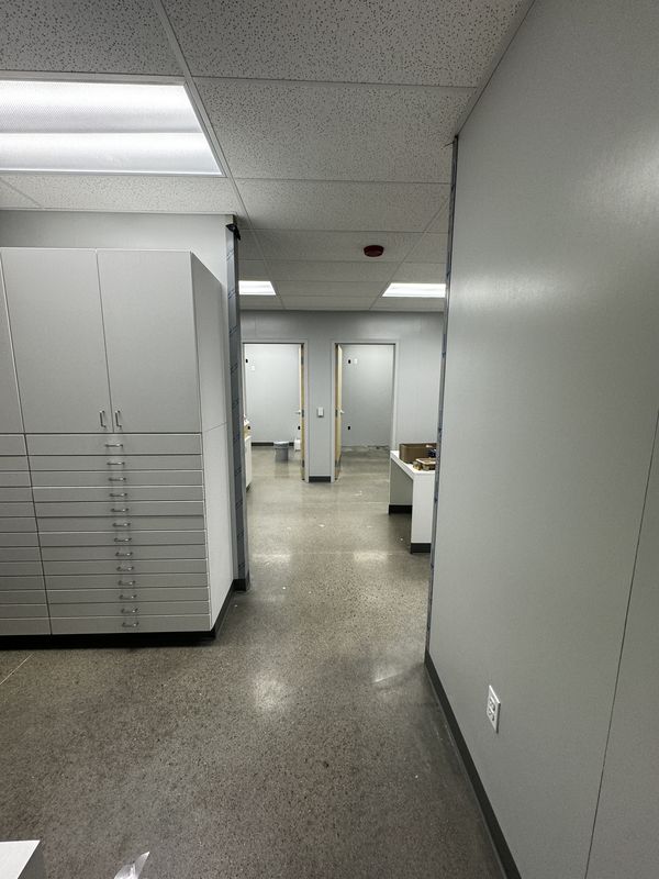 Finished back-room corridor with new ceiling grid, lighting, and receptacles