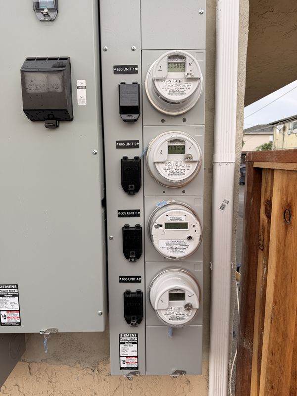 Four-unit meter stack with PG&E smart meters and labeled unit disconnects
