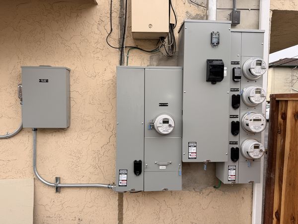 Multi-family service upgrade with new meter-mains and load centers on stucco wall