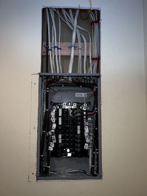 Panel interior with labeled circuits and new feeder cables routed above