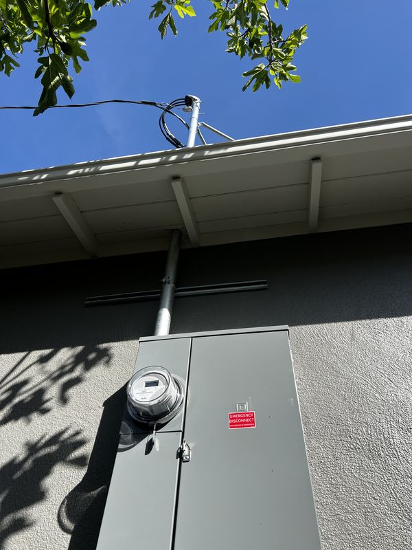 Service mast and new exterior panel with emergency disconnect under the eave