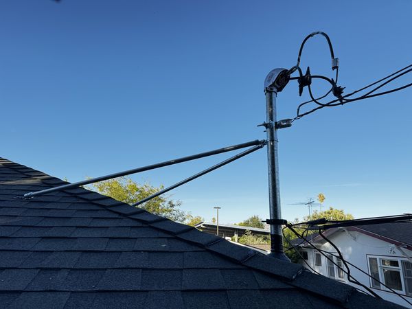 New service mast head with guy-wire bracing above the roof