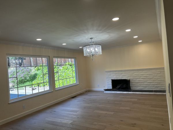 Finished living room with new recessed lighting, crystal chandelier, and fireplace wall after a whole-home rewire