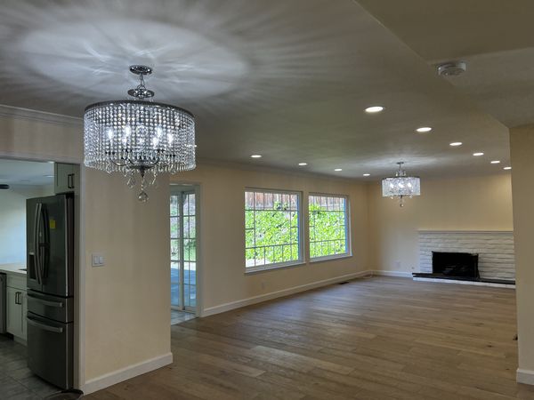 Open living and dining area with two crystal chandeliers and dimmable recessed lighting installed