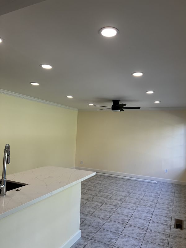 Kitchen and family area with new recessed lights, ceiling fan, and quartz island after the rewire