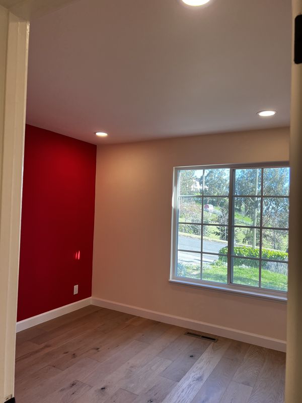 Bedroom with red accent wall, new recessed lighting, and tamper-resistant receptacles