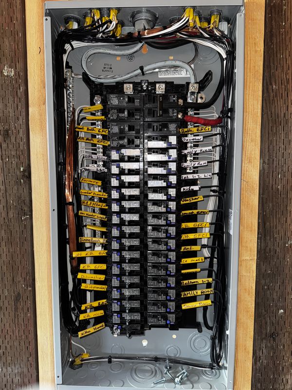 Load center interior with every breaker and home run hand-labeled before drywall