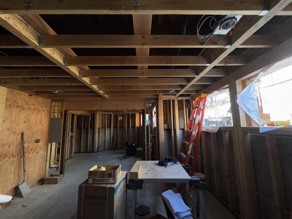 Rough-in stage with open ceiling framing and ladders on site