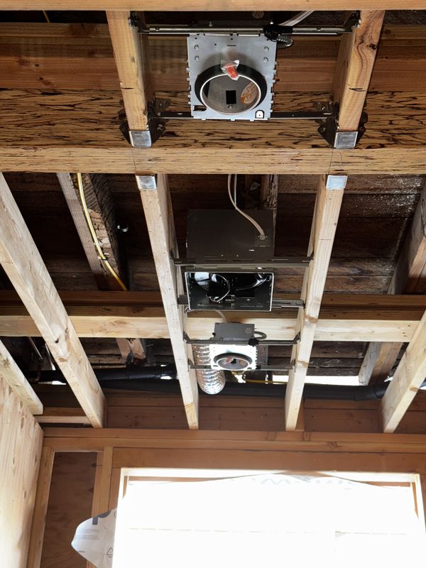 New-construction recessed light housings and bath fan rough-in between ceiling joists
