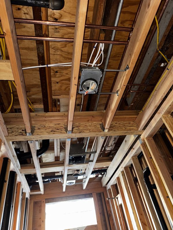 Ceiling rough-in with recessed light can, copper piping, and low-voltage runs